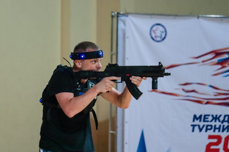 Боец LASERWAR целится из футуристического оружия.